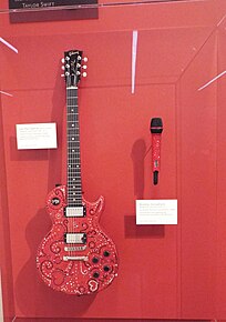 A red guitar and microphone attached to a wall