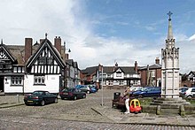 Sandbach market square, showing a black-and-white public house (left) and the war memorial (right), with Sandbach Crosses in the background