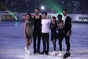 A photograph of Gabriella Papadakis, Guillaume Cizeron, Nathan Chen, Rika Kihira, Vanessa James and Morgan Cipres (from left to right) standing on the ice.