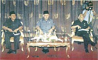 Harmoko (left) sitting alongside President Suharto and Vice President B. J. Habibie.