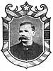 Framed portrait of a white man with an extremely bushy mustache, wearing a dark suit coat and bow tie.