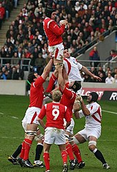 A Welsh player grasping the ball while being held in the air by his team-mates following a line-out