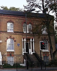 exterior of red bricked house, with blue plaque on front wall