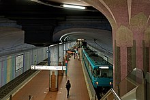 Underground station with island platform and roof supported by row columns along the centre of the platform