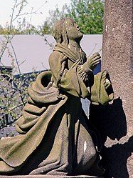 Mary Magdalene kneels in prayer at the foot of the cross