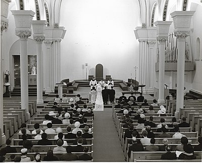 White plaster walls in 1970 wedding photo contrast to the previous ornamentation. Changes were made in the spirit of renewal inspired by Vatican II.