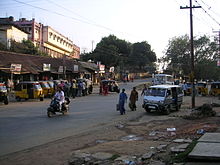 A road crossing showing pedestrians, and multiple vehicles such as auto-rickshaw, scooter, and van