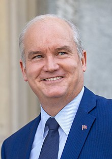 Photograph of O'Toole smiling. He is wearing a navy blue suit with a Canadian lapel pin.