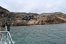 A two story building in black seen from the sea