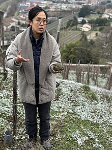 Chu Jaeok on the steep slopes of Château Grillet holding a large piece of granite.