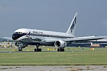 Side view of twin-engine jet touching down on runway, with deployed flaps and thrust reversers