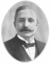 front portrait of man with mustache, well dressed with bow tie