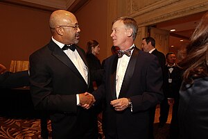 A photo of Williams dressed in a tux shaking hands with Colorado Governor John Hickenlooper at a 2012 school fundraising event for the Graduate School of Social Work's Bridge Project.