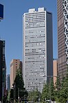 Ground-level view of a gray, window-dotted high-rise