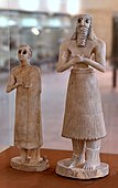 The god Abu (?) and a female statuette; 2800-2400 BC (Early Dynastic period); from the Square Temple of Abu at Tell Asmar (ancient Eshnunna (Iraq)); National Museum of Iraq. The loin-cloth has become recognizably a skirt and the twisted tufts have shrunk to a fringe[32]