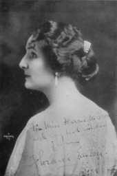 Head and shoulders rear-view studio portrait of an elegant lady in her thirties looking to her left. She is wearing a simple dress but has an elaborate hairstyle with jewellery. The portrait has been partially overwritten with a greeting and signature by the sitter.