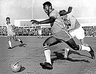 Photograph of a man dribbling a ball past an opponent