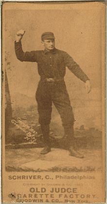 A sepia-toned blurry image of a man wearing an old-style dark-colored baseball uniform