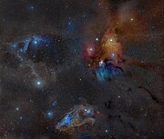 The large multicoloured Rho Ophiuchi cloud complex with the Dark River clouds (or Rho Ophiuchi Streamers) as Barnard 44 and 45 on the right, seemingly radiating towards the distant Pipe Nebula and the Galactic Center, extending from the core L1688 as well as L1689 dark nebulae.[8] In the lower part of this wide field image the distinct blue eyed (Nu Scorpii) Blue Horsehead Nebula can be seen. The blue area at the back of the head is IC 4601. The cloud in the top left corner is LBN 1093 and Sh2-1 with the bright star being Pi Scorpii and the yellowish cloud in the middle on the left being Sh2-7 with Dschubba at its center.