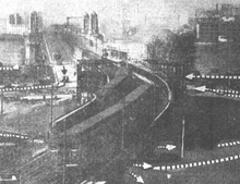A black-and-white image of a railway viaduct with a steel frame under construction around it