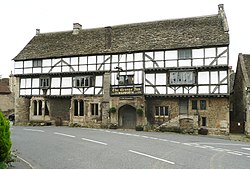 White fronted building with black beams prominent. Over the door is a sign saying The George Inn, Butcombe Brewing Company.