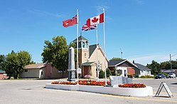 Flags and the war cenotaph in Cartwright with the Cartwright United Church in the background.