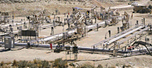 A photograph of Shell Oil's experimental in situ shale oil extraction facility in the Piceance Basin of northwestern Colorado. In the center of the photo, a number of oil recovery pipes lie on the ground. Several oil pumps are visible in the background.