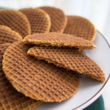 Thin, dark, round waffles; one cut in half shows a thin, internal layer of filling