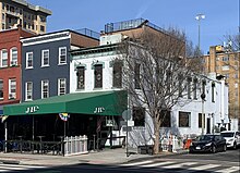 A white brick building on a corner, with a green awning reading "JR's"