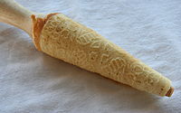 Krumkake just off the hot iron, being shaped on a conical rolling pin