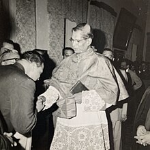 A man bends to kiss the ring of a Roman Catholic cardinal