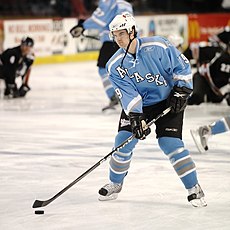 Right-handed hockey player on the ice in a powder blue uniform