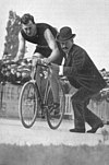 A male cyclist getting an assisted push from a pedestrian