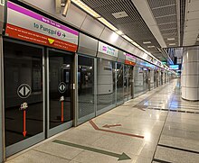 The station platform is separated from an incoming train by the platform screen doors.