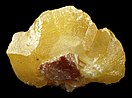 A yellow crystal elongated on its sides, with a small attached cerussite in front