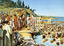 A painting which shows a Christian priest standing on a pier officiating the baptism of multiple people who are standing in a water body while other people watch on