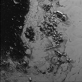 This image shows a region at the border between Belton's "head" (left) and the light, flat Sputnik Planitia (right), with Hillary Montes at center.