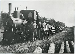 A monochrome photograph of a steam locomotive hauling logs, and its crew