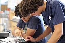 Two male student look over a pulmonary machine.