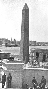 An Egyptian obelisk, standing near structures in Alexandria, Egypt