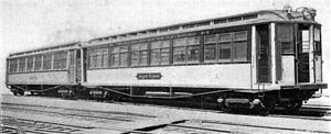 A photo of IRT Composite Prototypes. This photo is in black and white, and shows two wooden railcars, built circa 1902, on some railroad tracks.