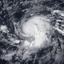 A satellite image of a powerful hurricane over the Central Pacific Ocean; it has a circular eye, a thick and round central region of clouds, and pronounced spiral bands on its eastern flank