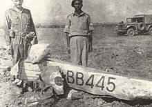 Wreckage of a plane, surrounded by two men