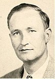 White male with dark hair in a tan suit