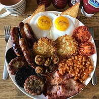Full English breakfast (19th century) with sausage, bacon, beans and tomatoes (from the Americas, by 18th century[60]) and eggs