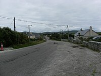 A long road, with stone walls and mountains in the background