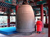 Image shows bell about three metres high, with celebrant alongside