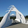 View through the curved arch structure of a steel bridge, with a mountain in the background