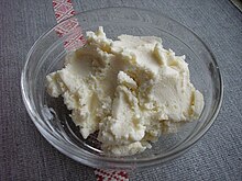 Low-angle shot of Bryandza cheese in a glass bowl on textile surface.