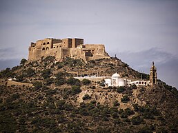 Fort atop a hill with a mosque in the foreground at a lower elevation